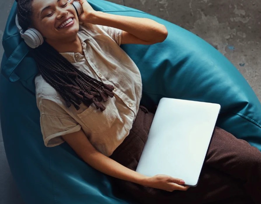 A guest smiling while relaxing with headphones and a laptop